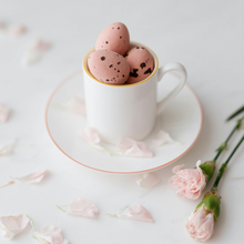Load image into Gallery viewer, Pink mini eggs in a mini teacup, surrounded by small pink roses and petals
