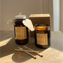 Load image into Gallery viewer, Sustainable safety matches in amber glass jar next to unlit essential oil soy wax candle with a few loose matches on table in front.
